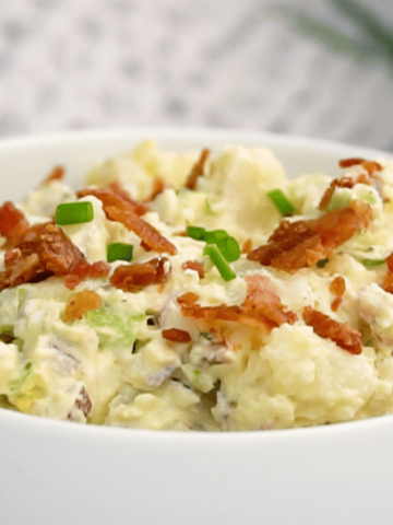loaded potato salad garnished with green onion and crispy bacon by FarmhouseHarvest.net