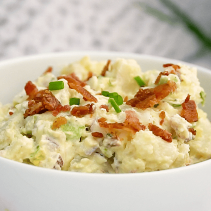 loaded potato salad garnished with green onion and crispy bacon by FarmhouseHarvest.net