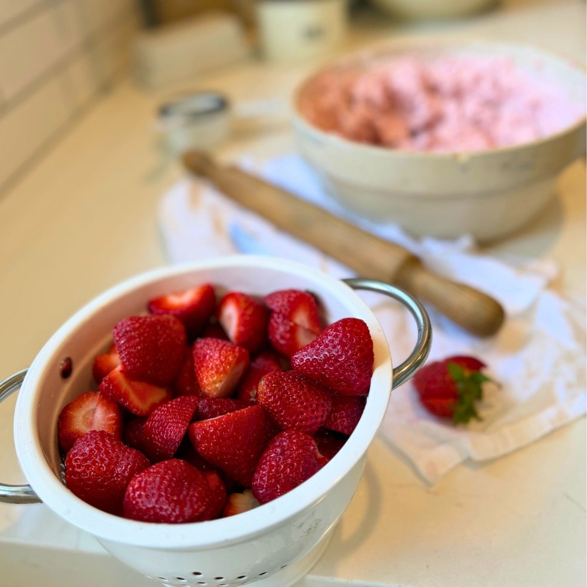 fresh washed strawberries in a colandar and strawberry cream in a bowl