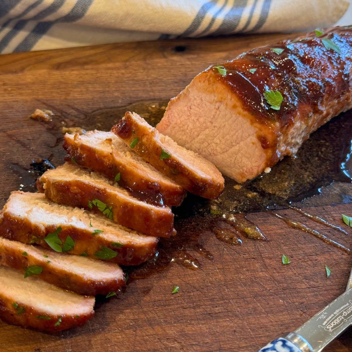 a tender juicy grilled pork tenderloin brushed with BBQ sauce sliced on cutting board