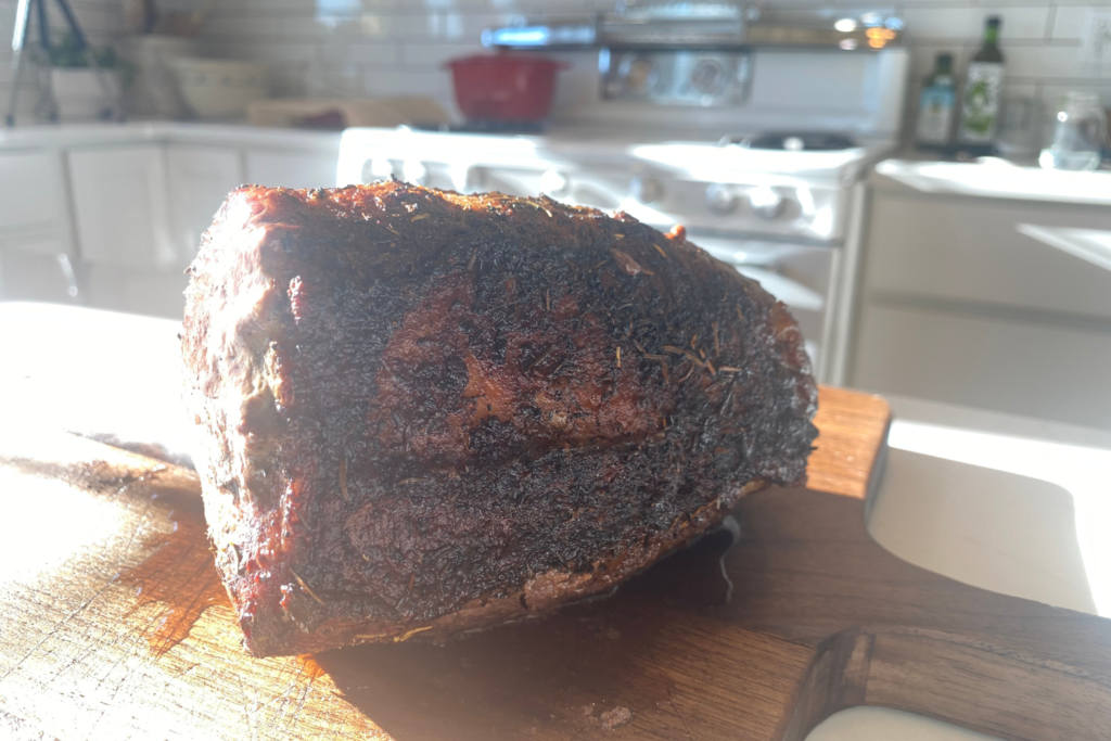 roast with herb crust resting on cutting board