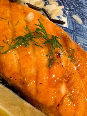 glazed smoked salmon on blue plate garnished with fresh dill and a lemon wedge