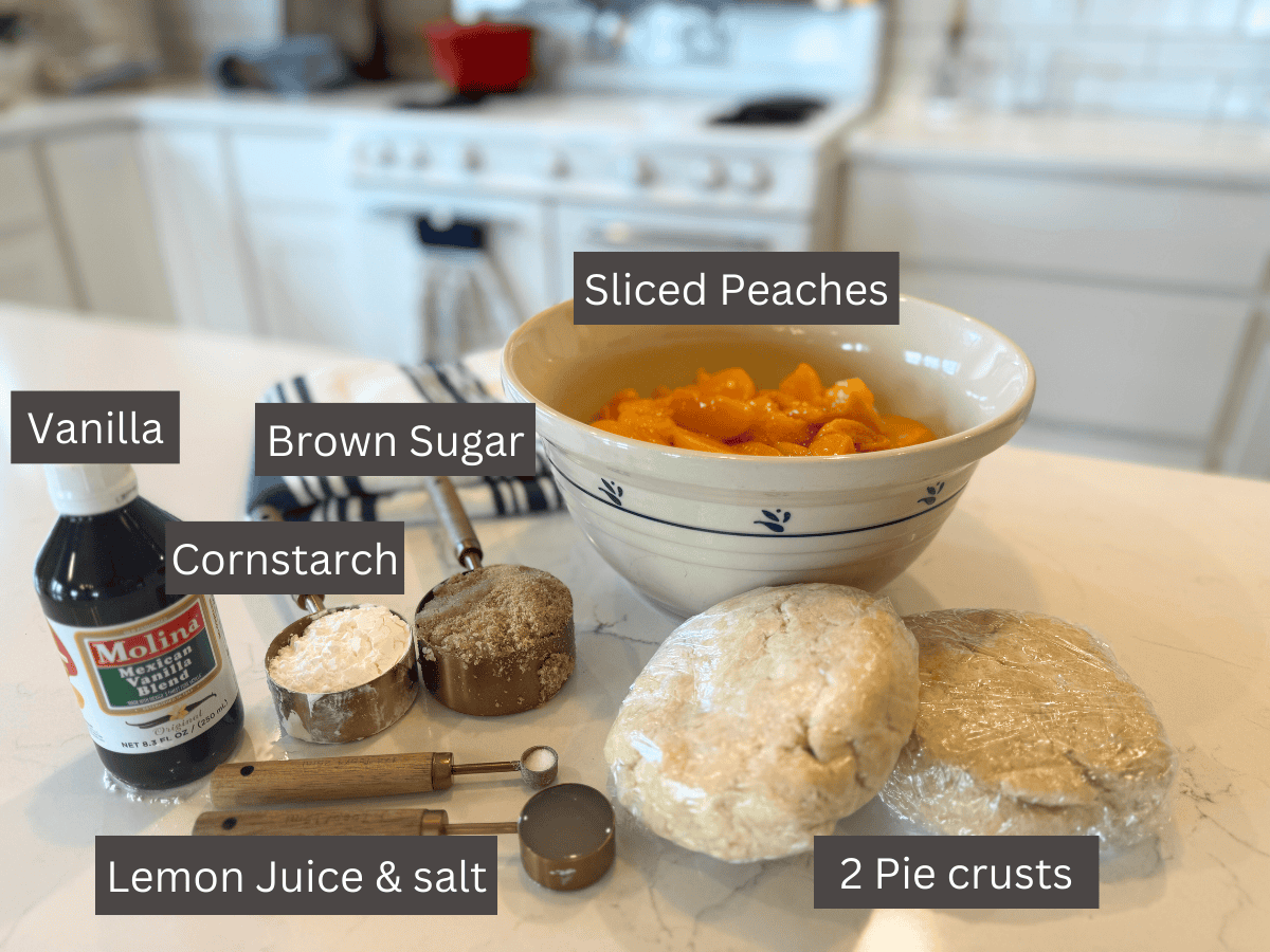 peach pie ingredients: sliced peaches in bowl, 2 disks of raw pie dough, brown sugar, cornstarch, vanilla extract, lemon juice and salt