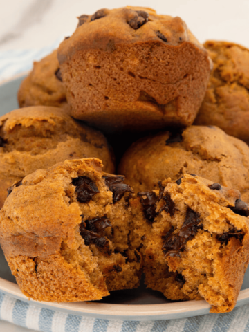 pumpkin chocolate chip muffins on a plate one is opened up