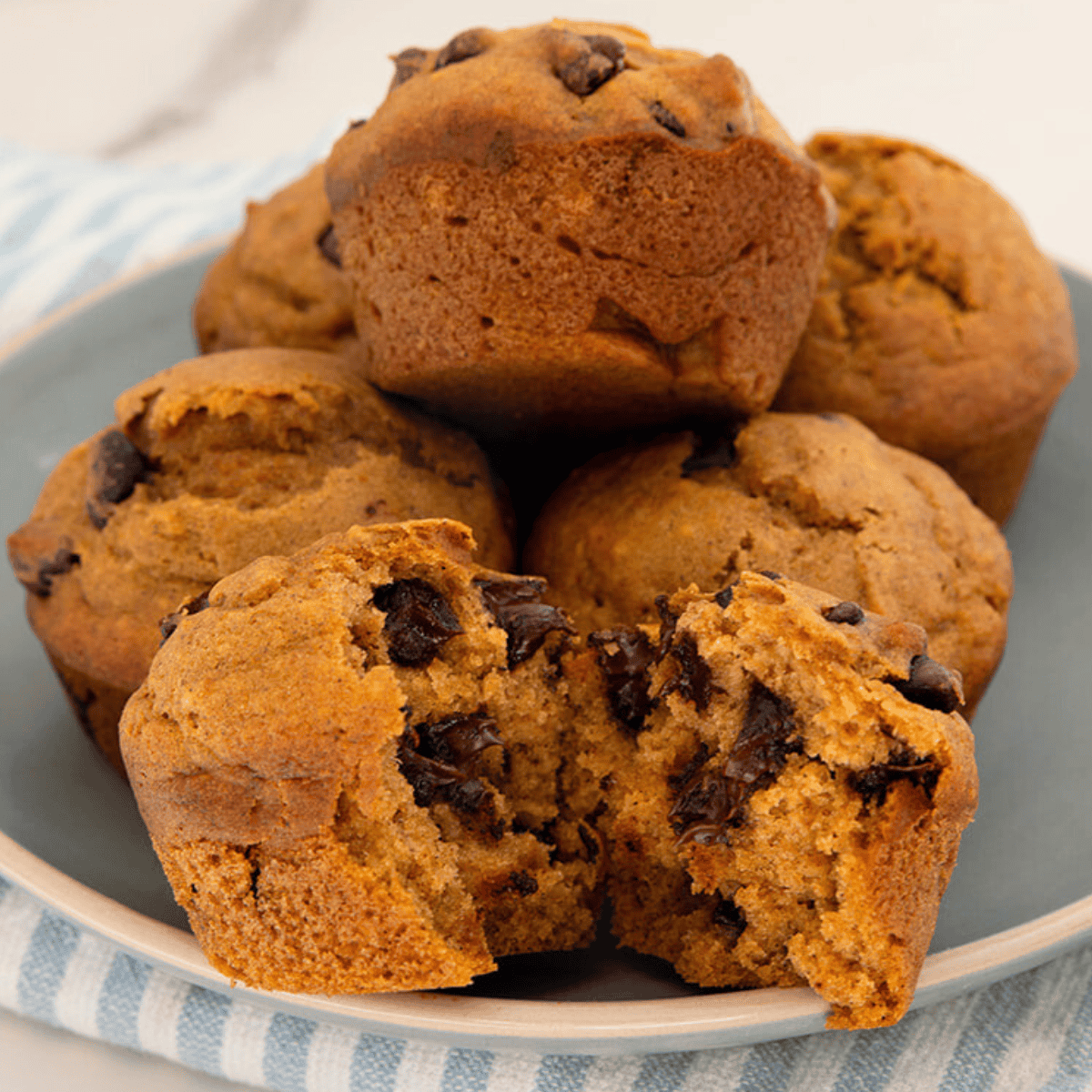 pumpkin chocolate chip muffins on a plate one is opened up