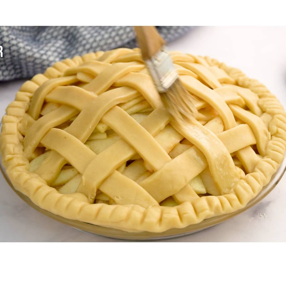 brushing the top of the pie with melted butter