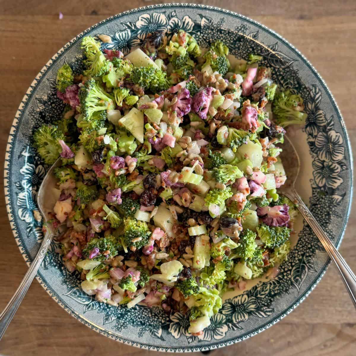 bacon croccoil salad in blue bowl on cutting board with serving spoons