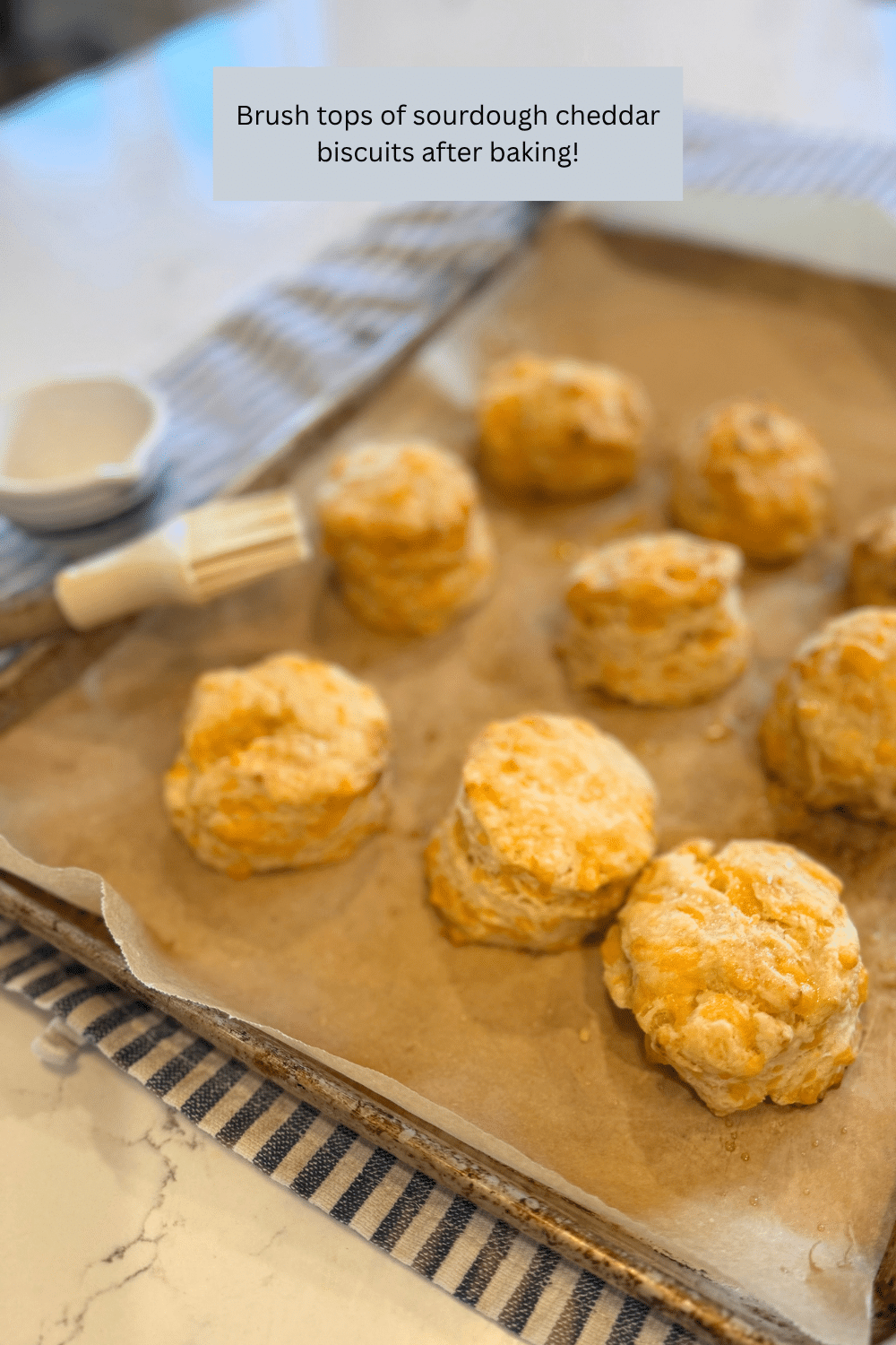 brushing tops of sourdough cheddar biscuitsa after baking