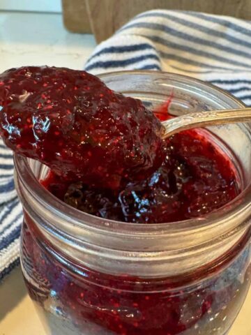 huckleberry freezer jam on spoon on jar of jam.