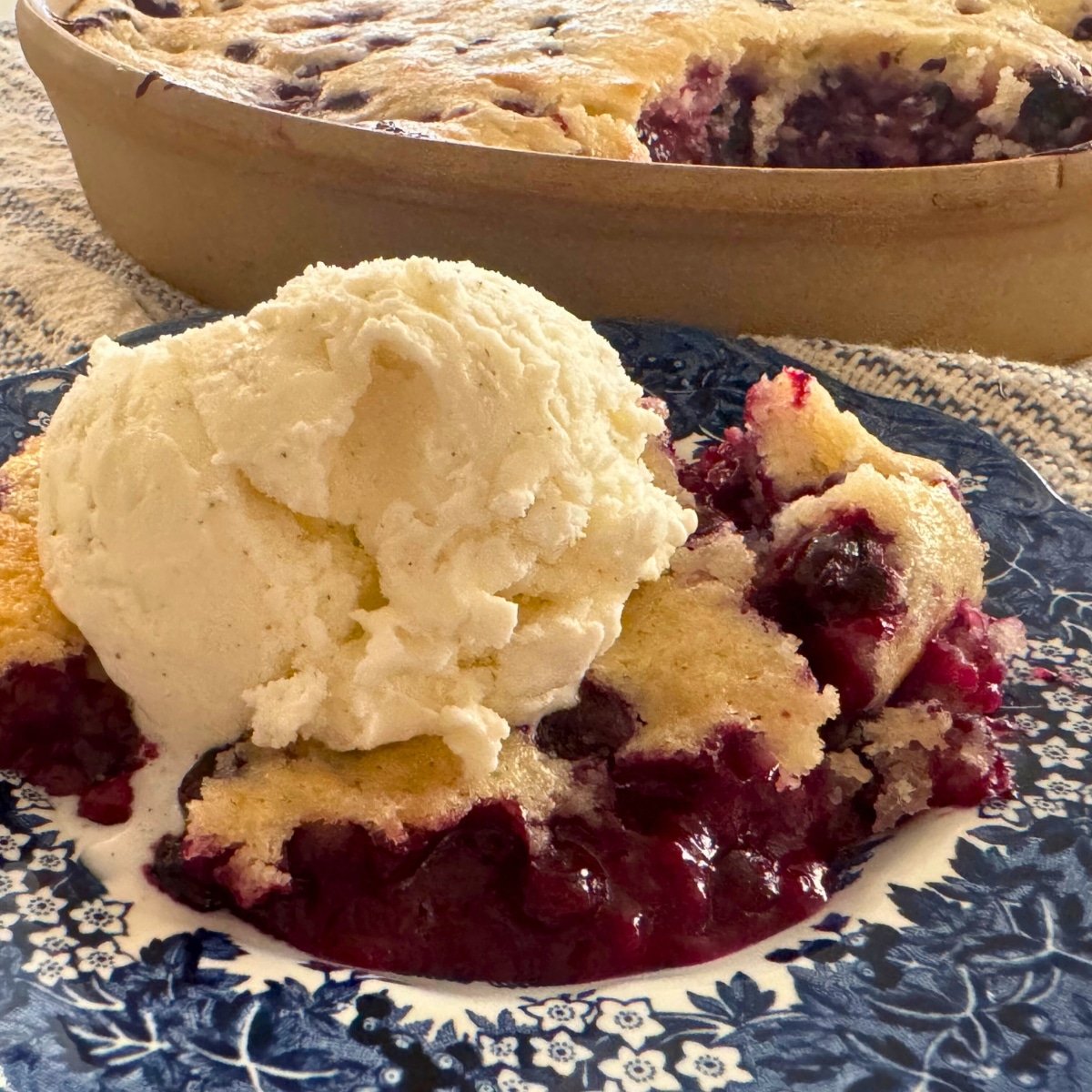 huckleberry cobbler served on plate with vanilla ice cream