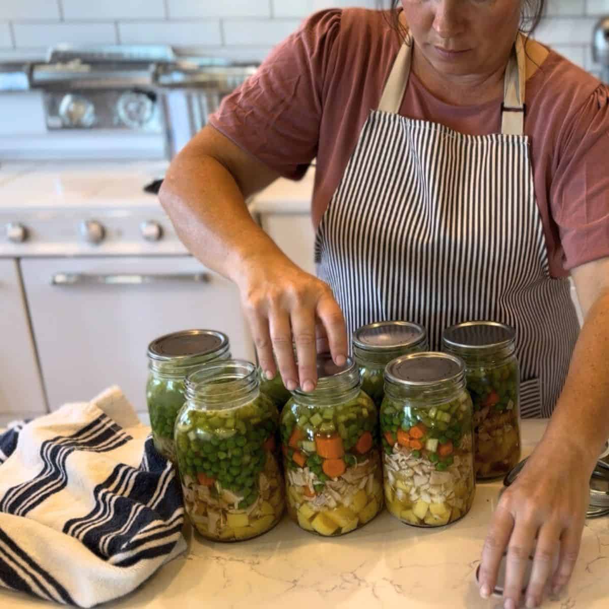 placing lids on jars of chicken pot pie filling