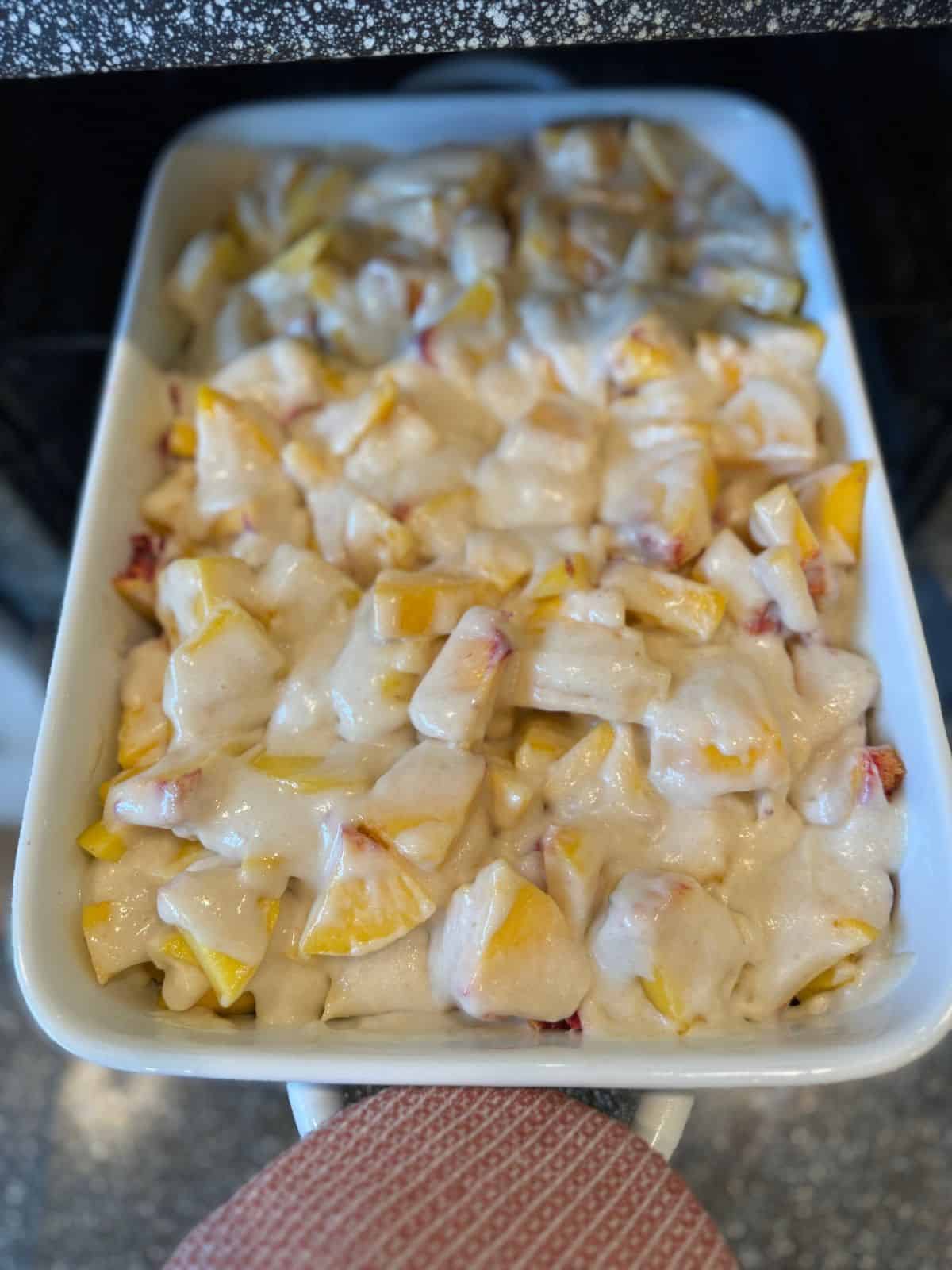 placing sourdough peach cobbler into the oven to bake