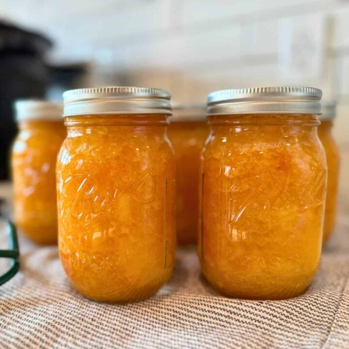 low sugar peach jam canning recipe in jars on cloth on counter