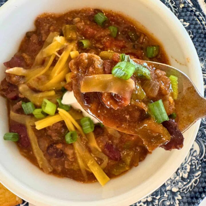 a bowl of crockpot chili garnished with cheese and a spoonful to show texture