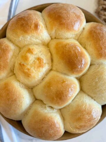 killer rolls recipe baked in round stoneware cake pan baked and buttered with kitchen towel