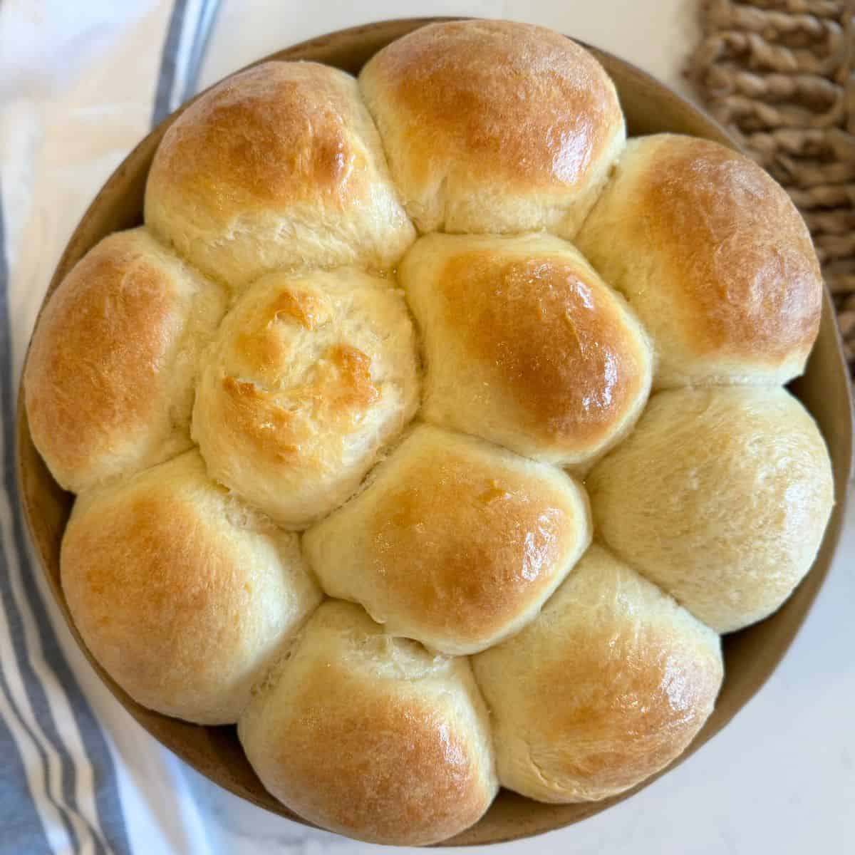 killer rolls recipe baked in round stoneware cake pan baked and buttered with kitchen towel