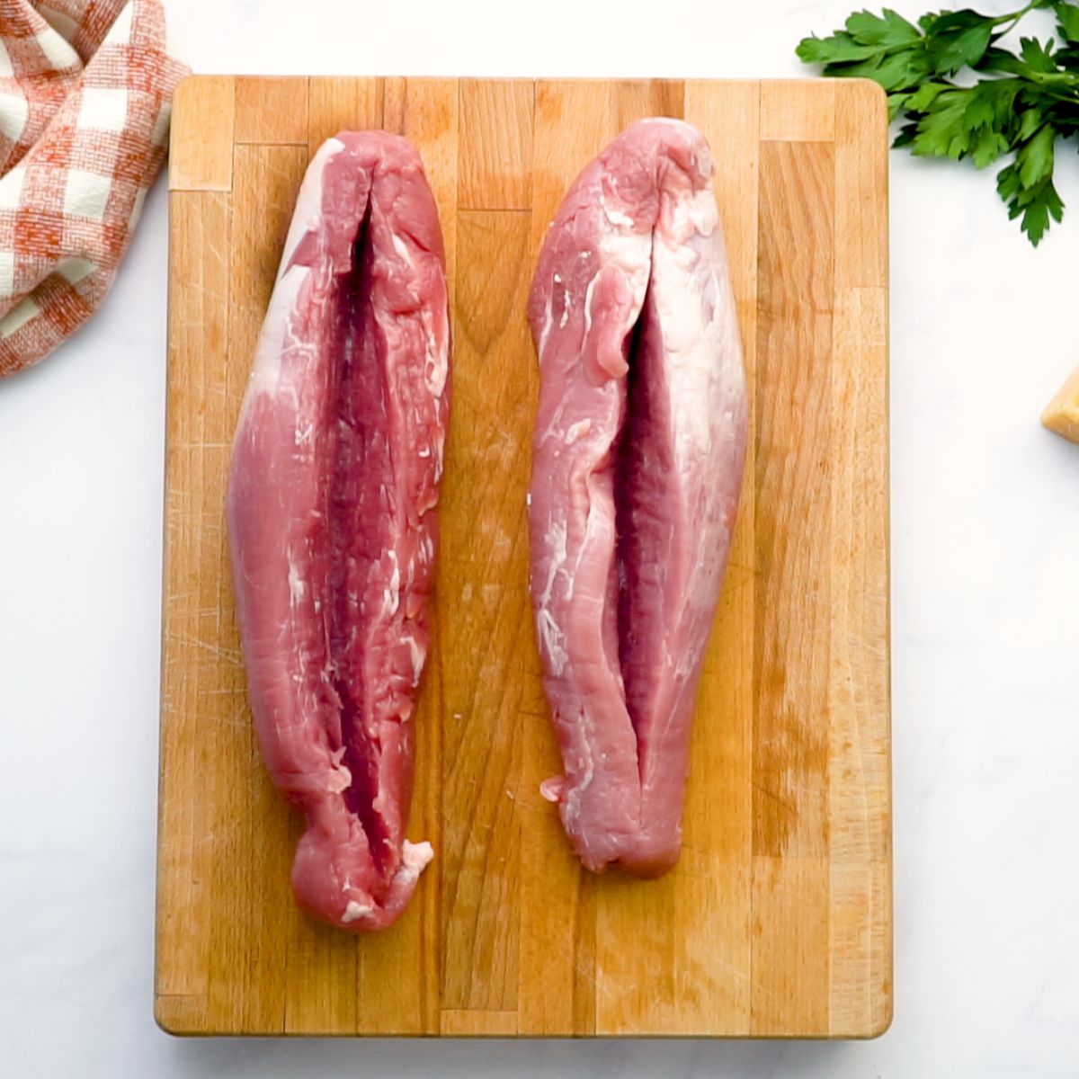 raw pork loins sliced for stuffing on cutting board