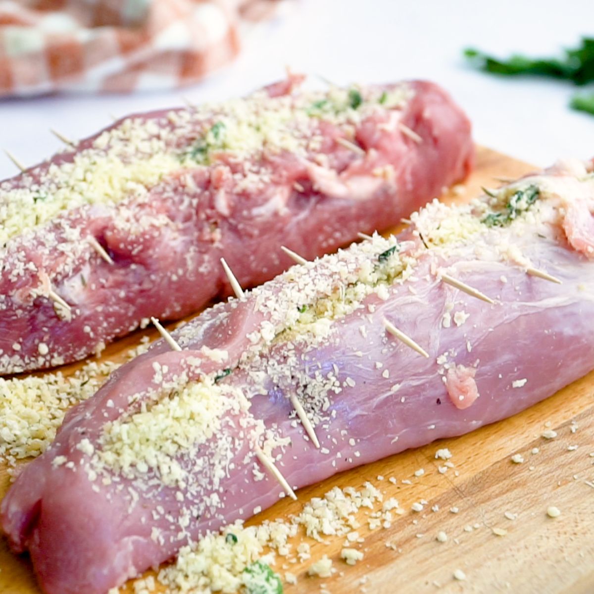 raw stuffed pork loin on a cutting board closed with toothpicks