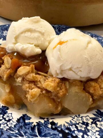 simple pear crisp recipe served on a blue plate with vanilla ice cream and a drizzle of caramel