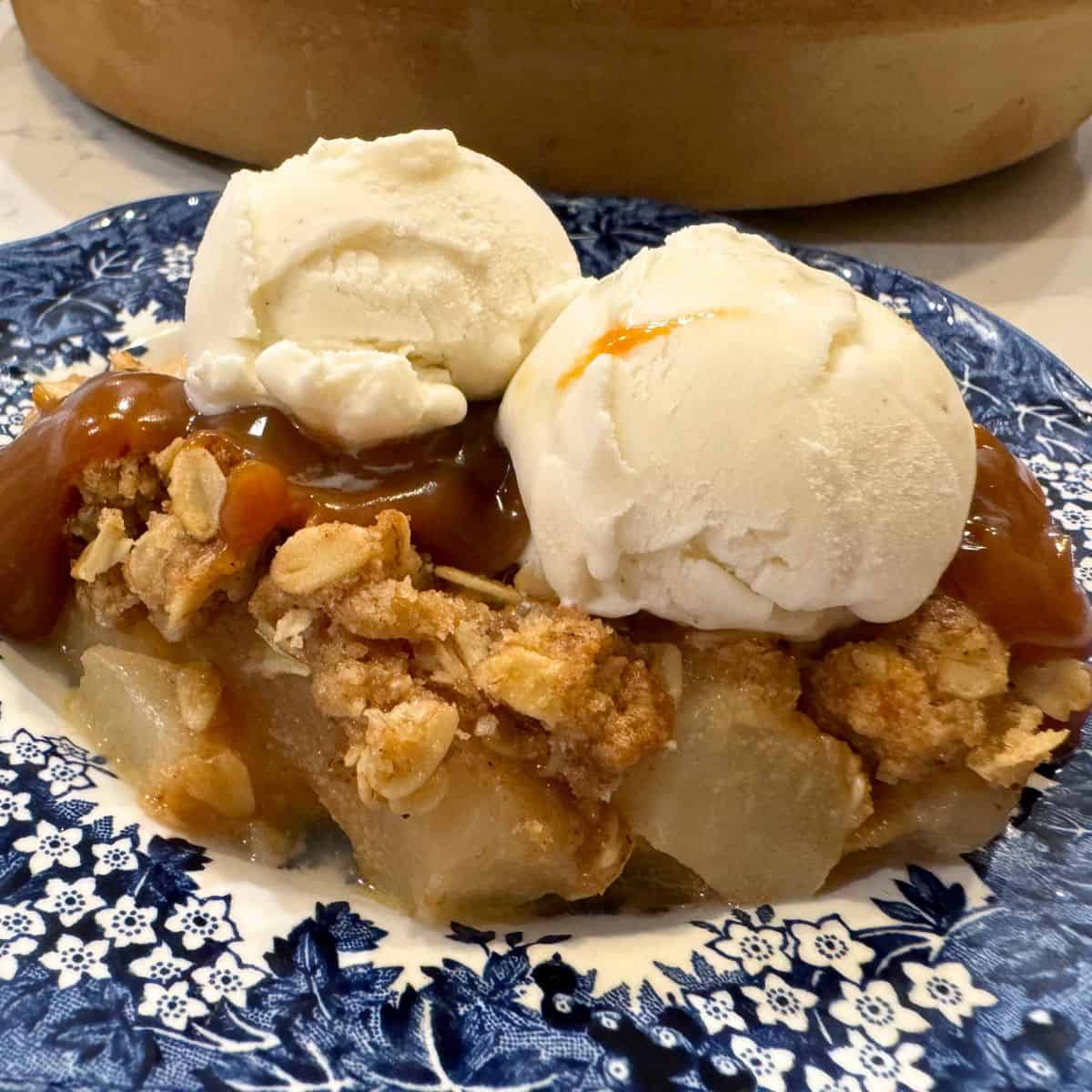 simple pear crisp recipe served on a blue plate with vanilla ice cream and a drizzle of caramel