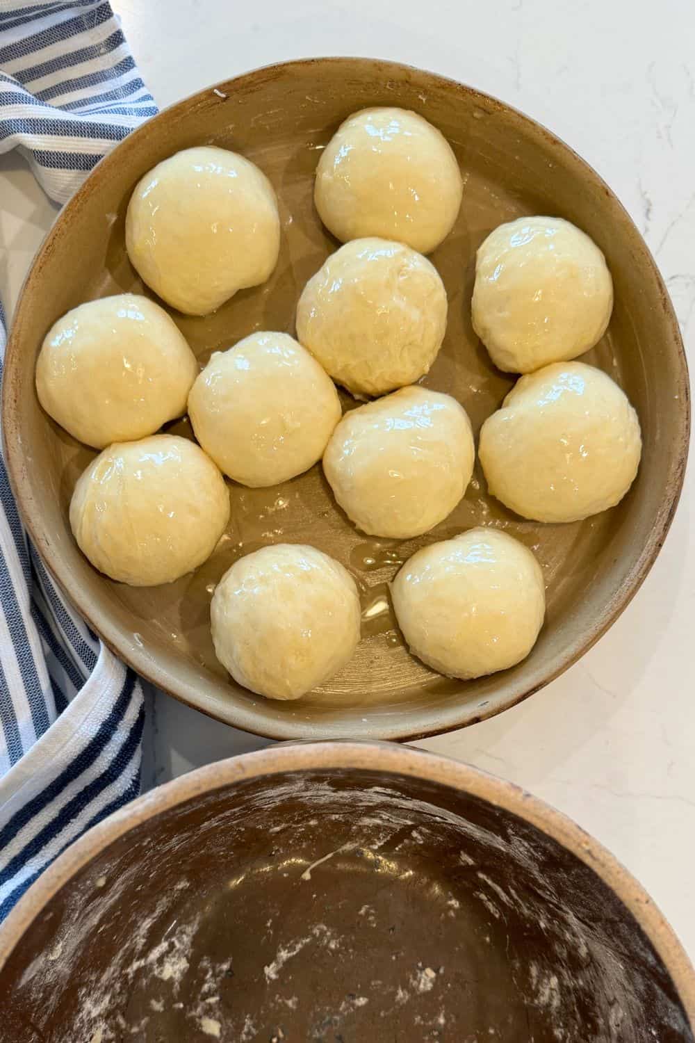 roll dough shaped in baking dish with melted butter brushed over top