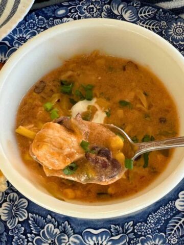 taco chicken soup in a blue bowl with a spoonful lifted up to show texture