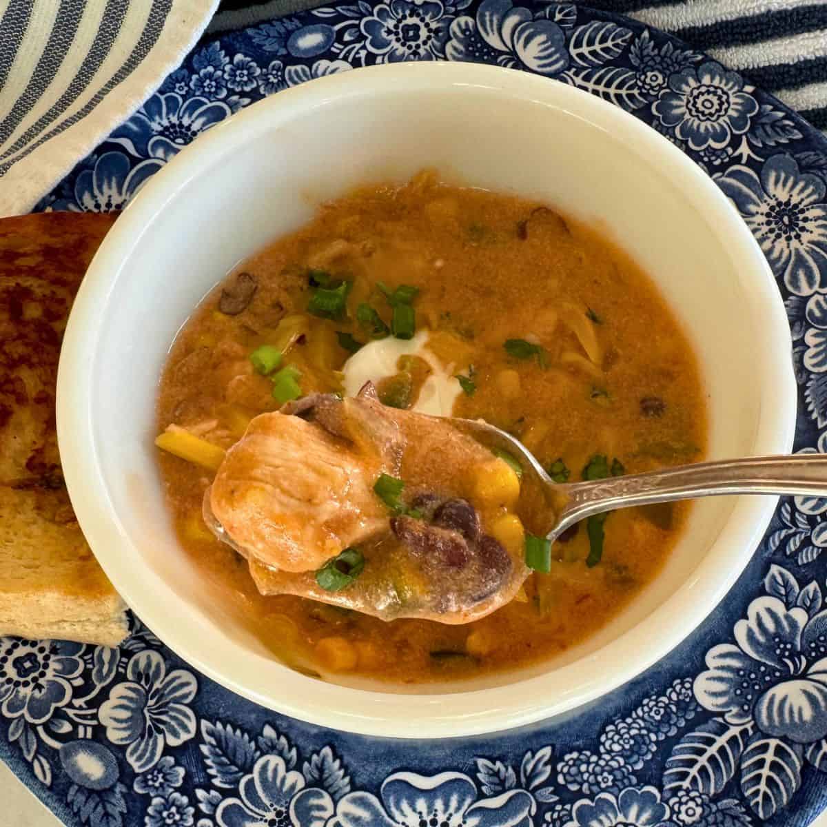 taco chicken soup in a blue bowl with a spoonful lifted up to show texture