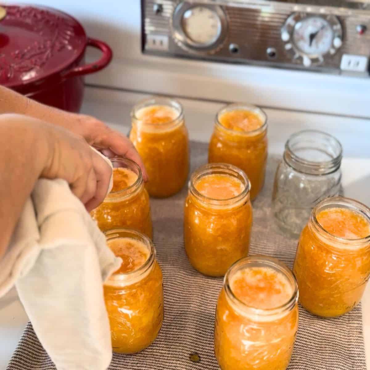 wiping rims of filled jars with a clean towel