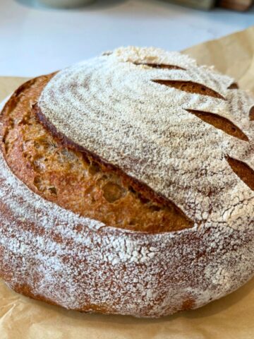 90% Einkorn sourdough bread recipe loaf cooling on counter on parchment paper