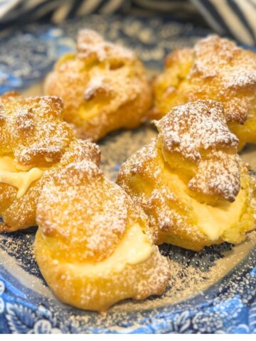 vanilla cream filled cream puffs on a blue plate