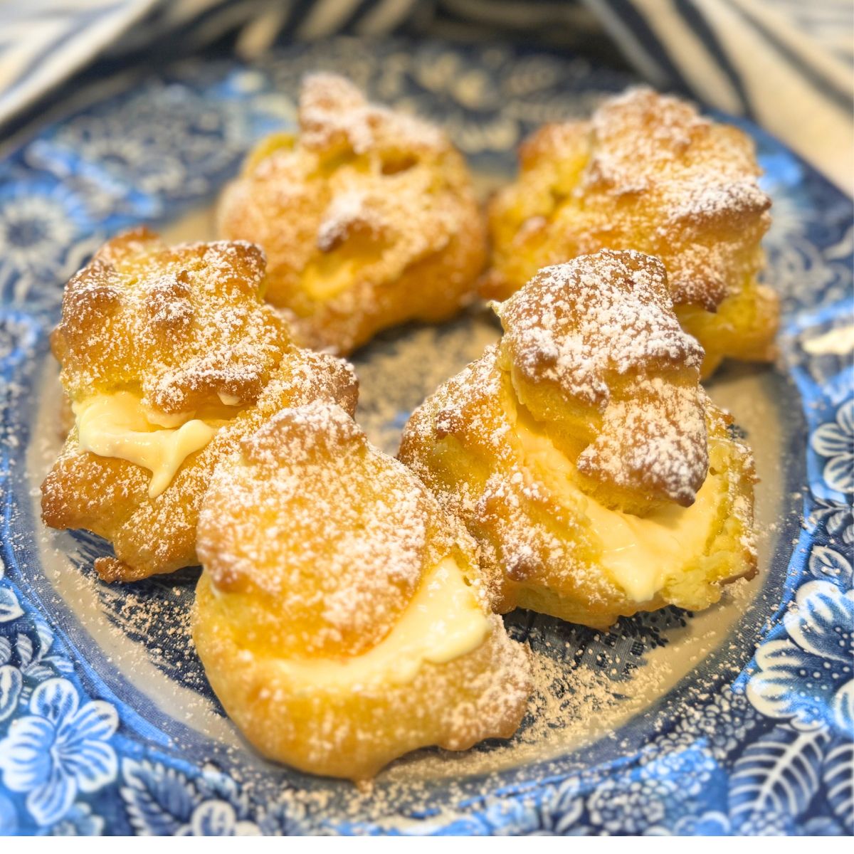 vanilla cream filled cream puffs on a blue plate