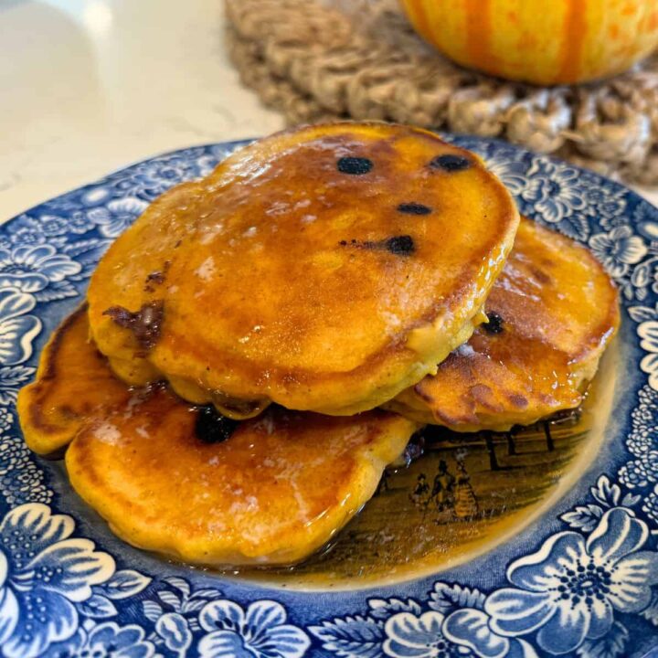 fluffy pumpkin chocolate chip pancakes on a blue plate with butter and maple syrup. #pumpkin #pancakes