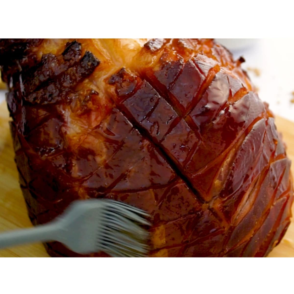 brushing pineapple glaze on scored whole ham