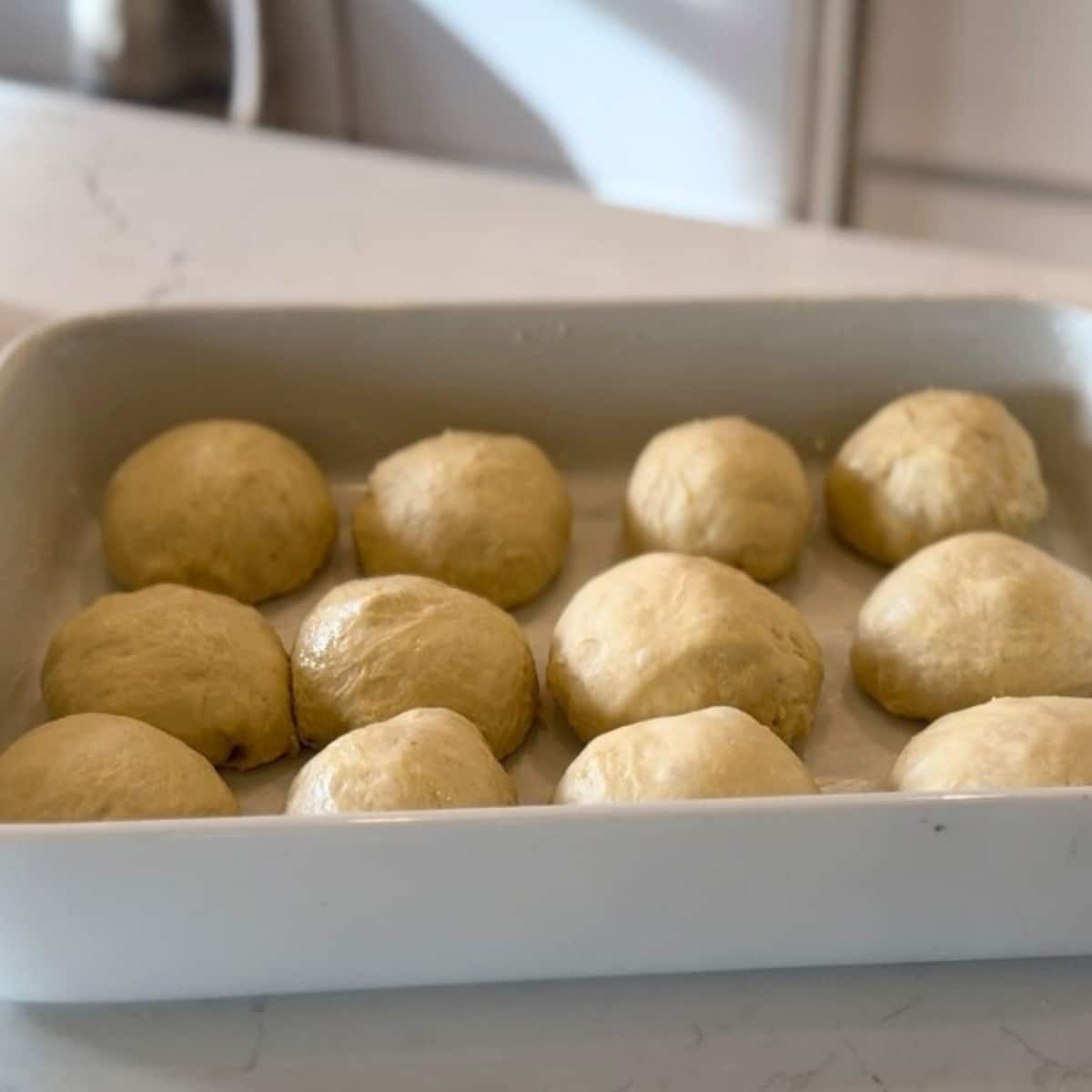 uncooked sourdough rolls in baking dish