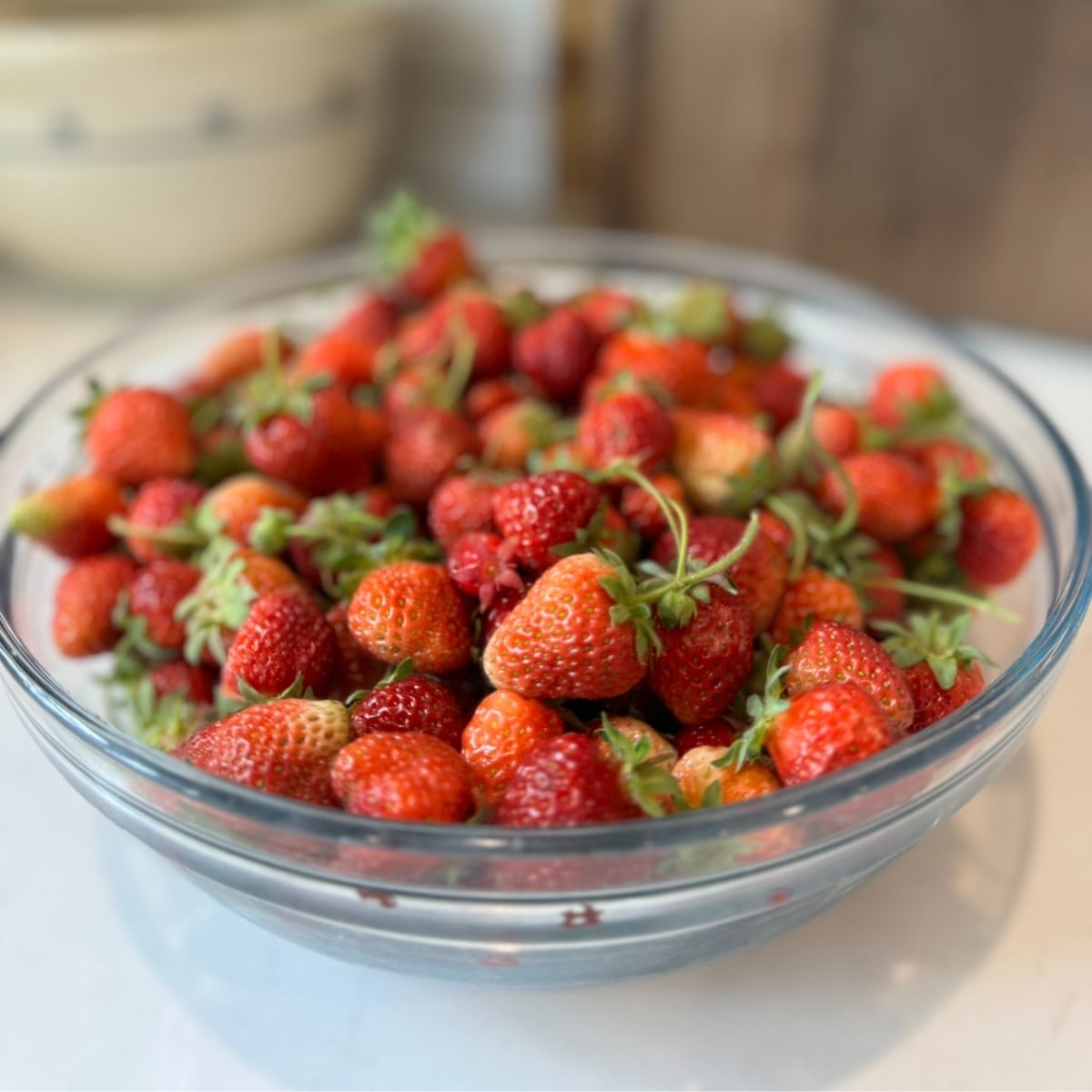 fresh picked strawberries from the garden in a clear bowl on the counter