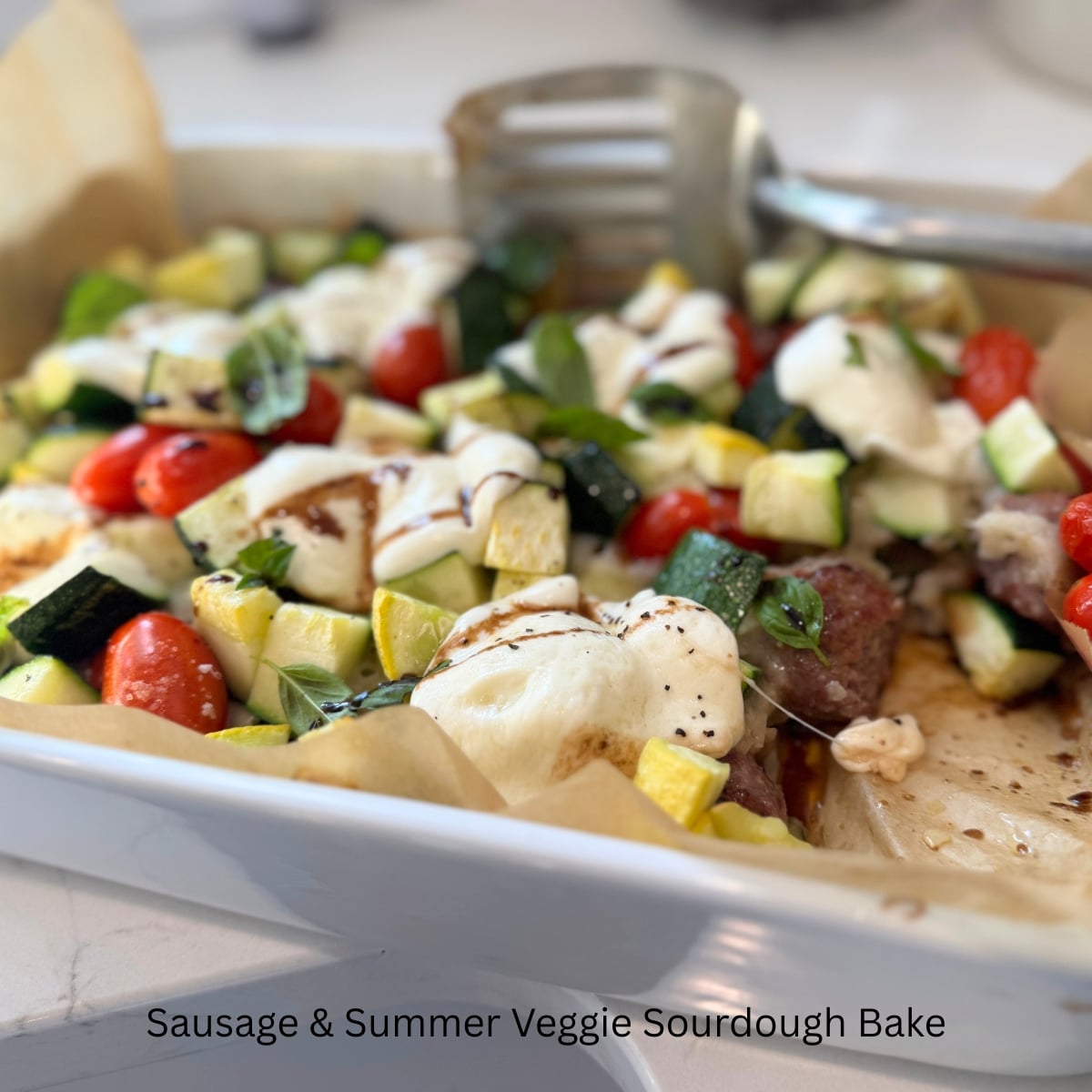 Sausage & Summer Veggie Sourdough Bake in baking dish with spatula