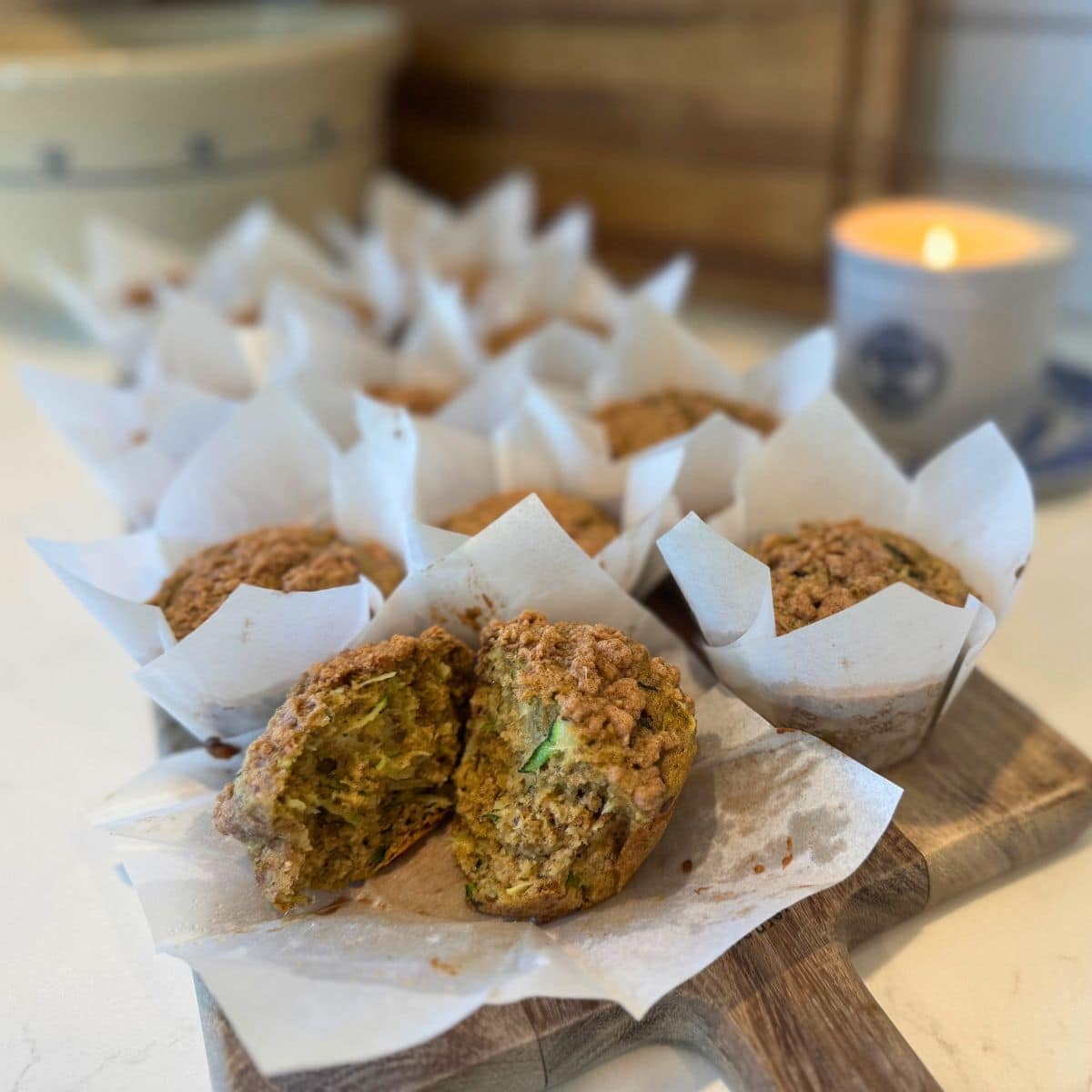 sourdough zucchini muffins cooling on a wood cutting board with one torn open to show crumb