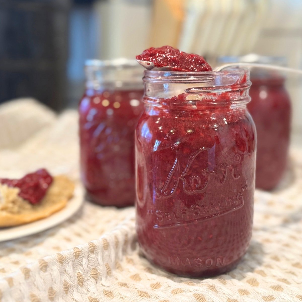 blackberry jam canning recipe on spoon, in jars, and on a roll