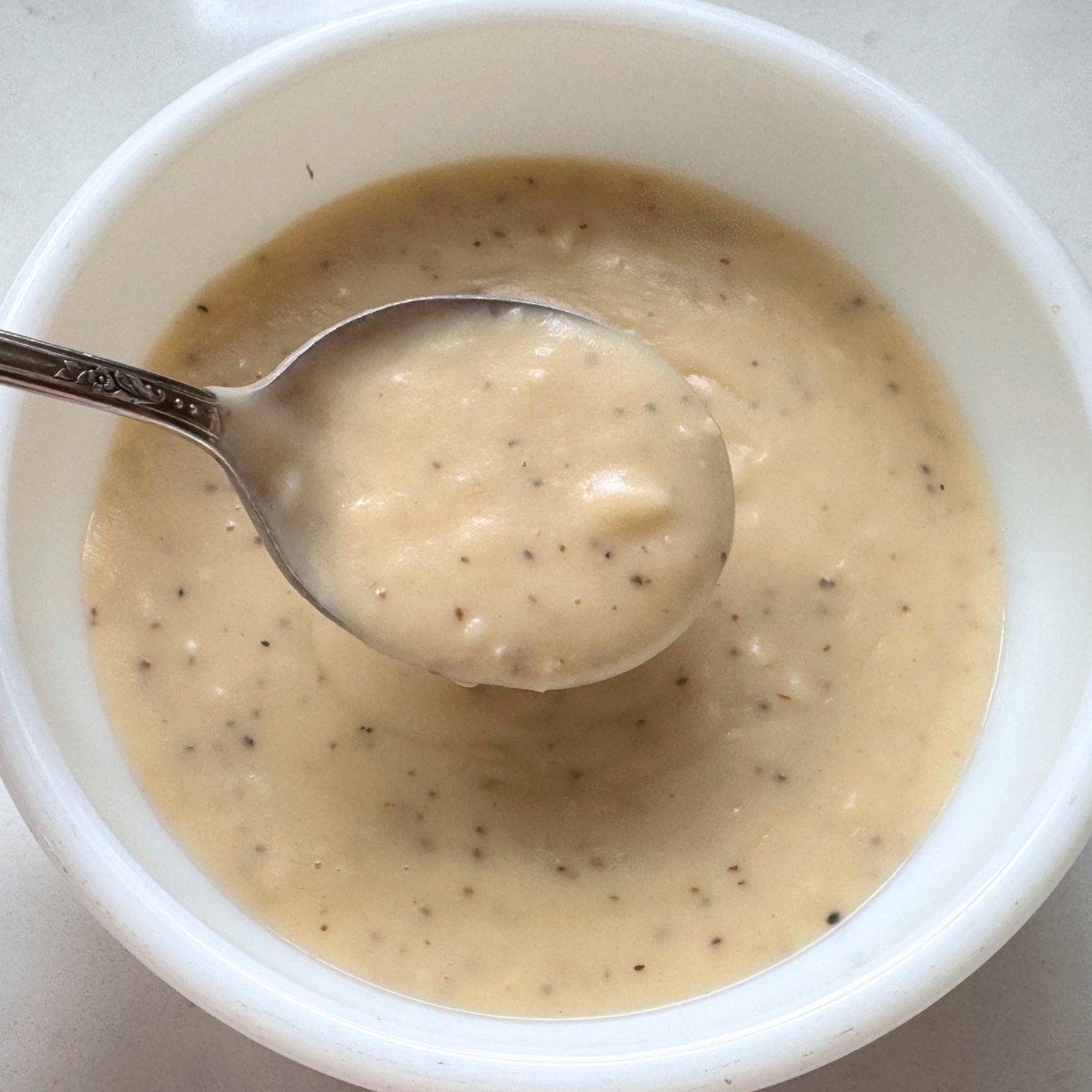 Homemade Cream of Chicken Soup condensed in a serving bowl and on spoon up close to show texture