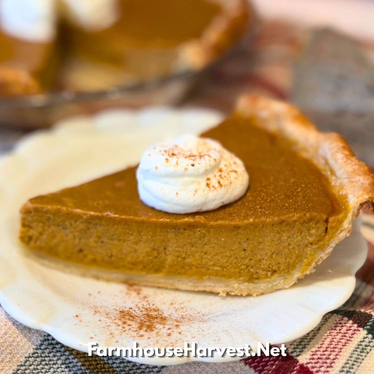 a slice of easy pumpkin pie on white plate with whipped cream and dust of cinnamon with "farmhouseharvest.net" branding at bottom
