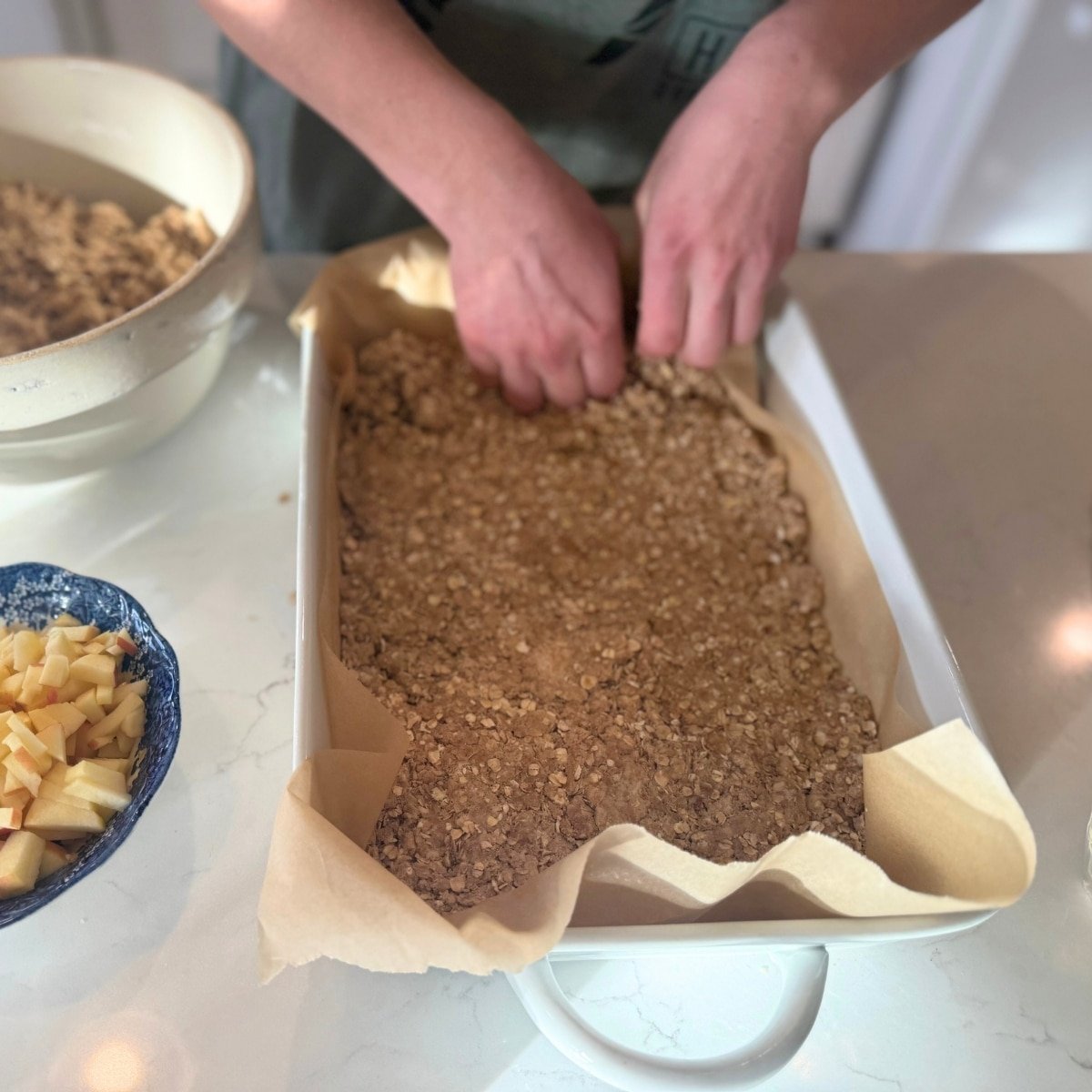 pressing bottom layer down in baking sheet for sourdough apple breakfast bars