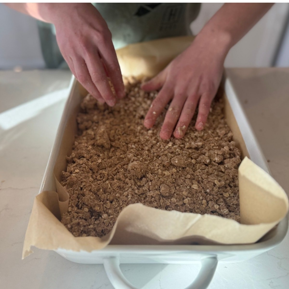 pressing down top layer in baking sheet for sourdough apple breakfast bars