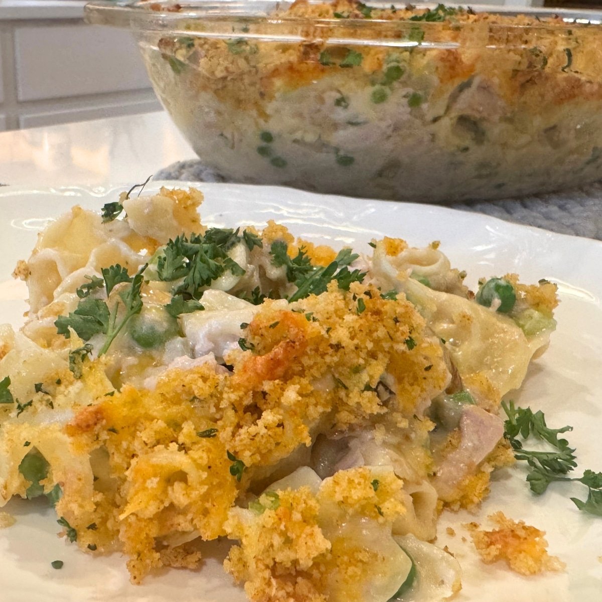 crispy topped tuna casserole in dish and plated with fresh parsley garnish