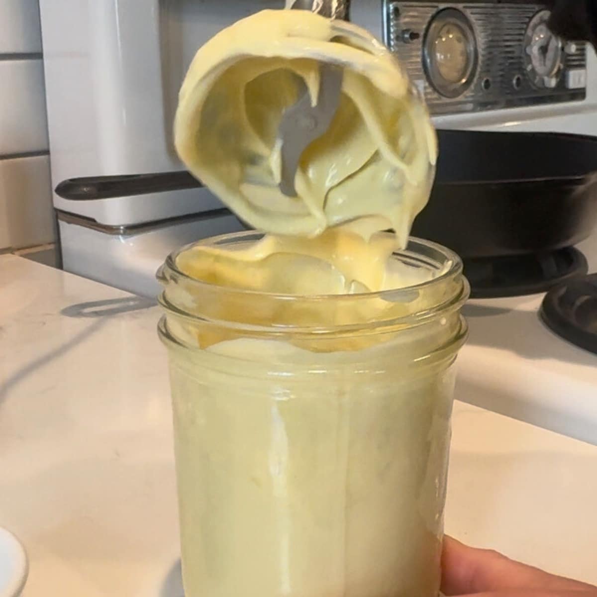 homemade mayo in a mason jar with the emersion blender coming up