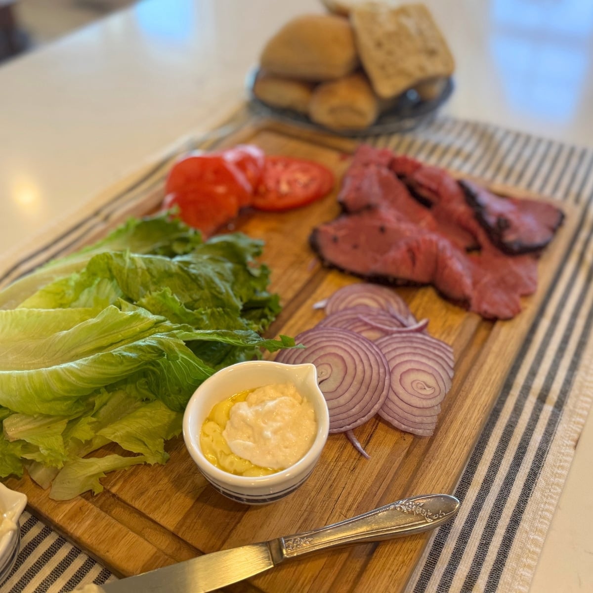 Ingredients for roast beef sandwich on sourdough ciabatta rolls including horseradish mayo and red onions