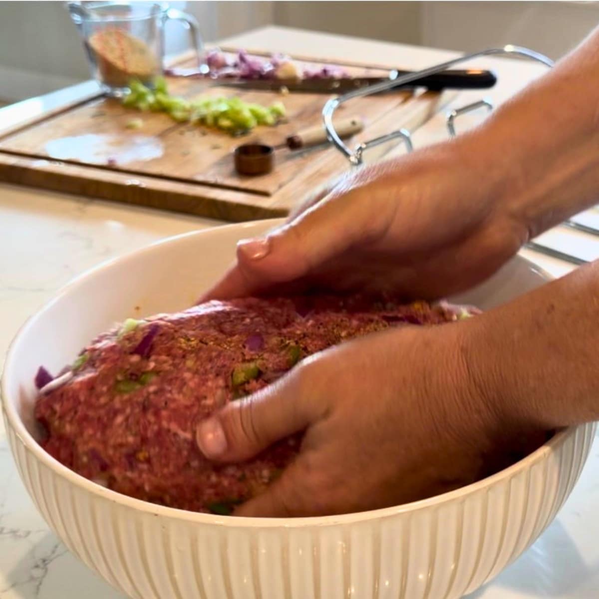 hands in mixing bowl shaping meatloaf in bowl