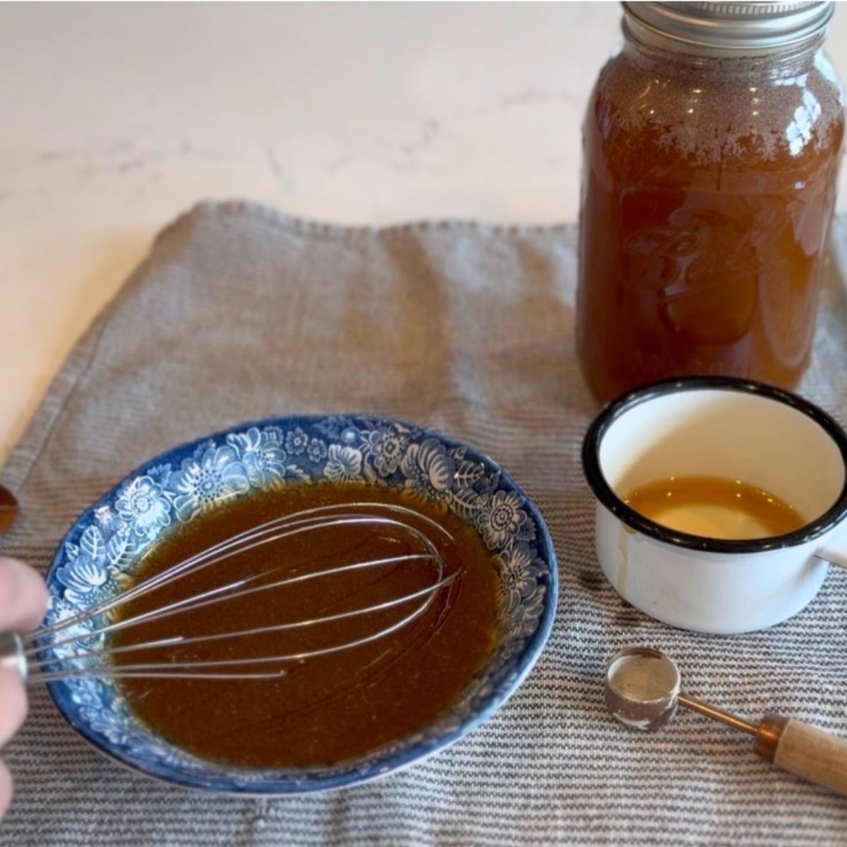 a jar of honey a bluw bowl with honey in it and with a whisk, a teaspoon with pectin on it.... Just finished whisking pectin into honey in bowl