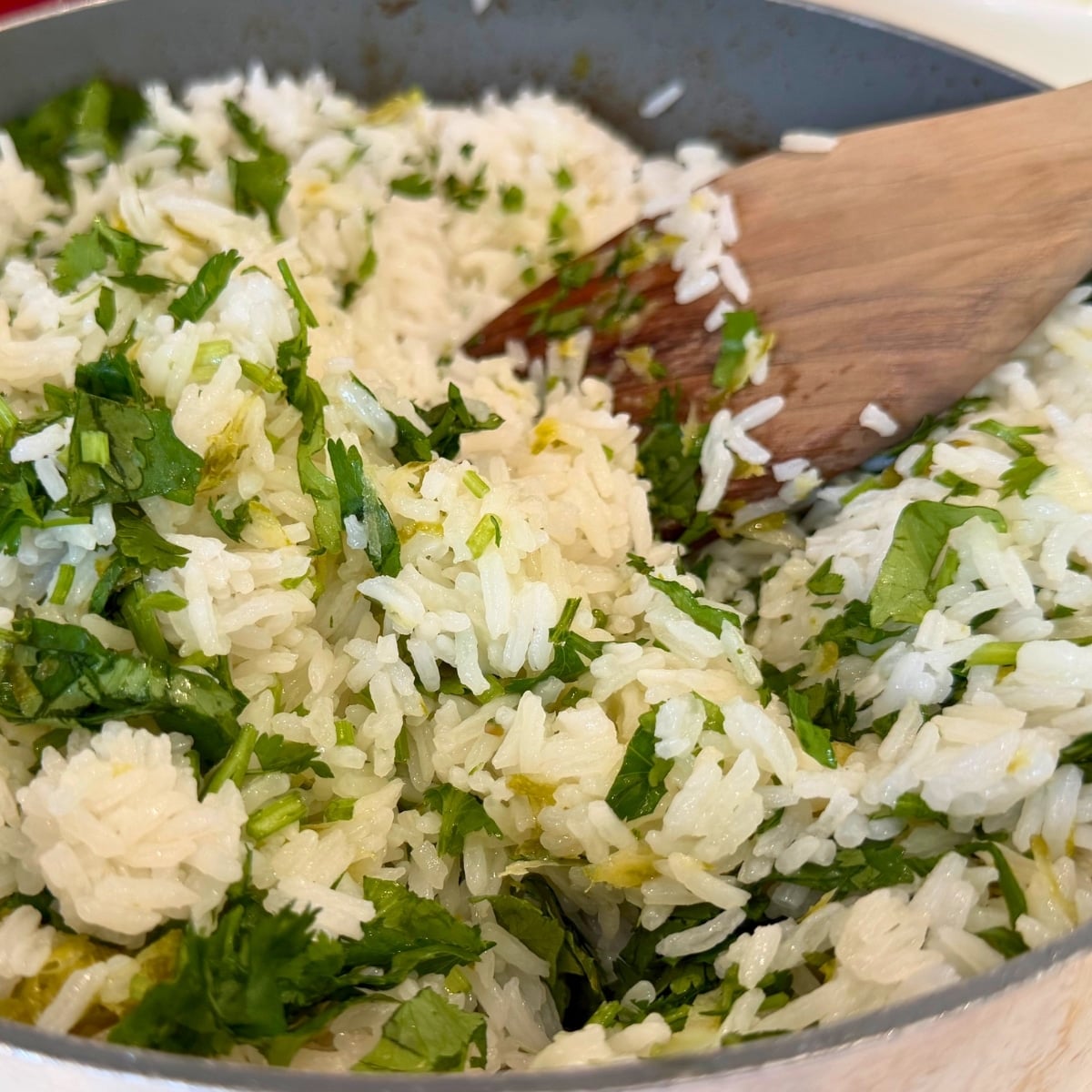 cilantro lime rice in skillet with a wooden spatula