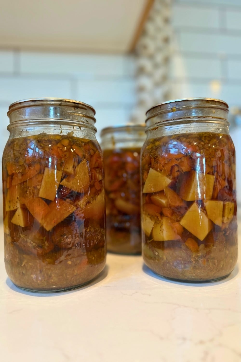 jars on raw packed beef stew with beef, potatoes, carrrots, onion and celery in layers in the jar