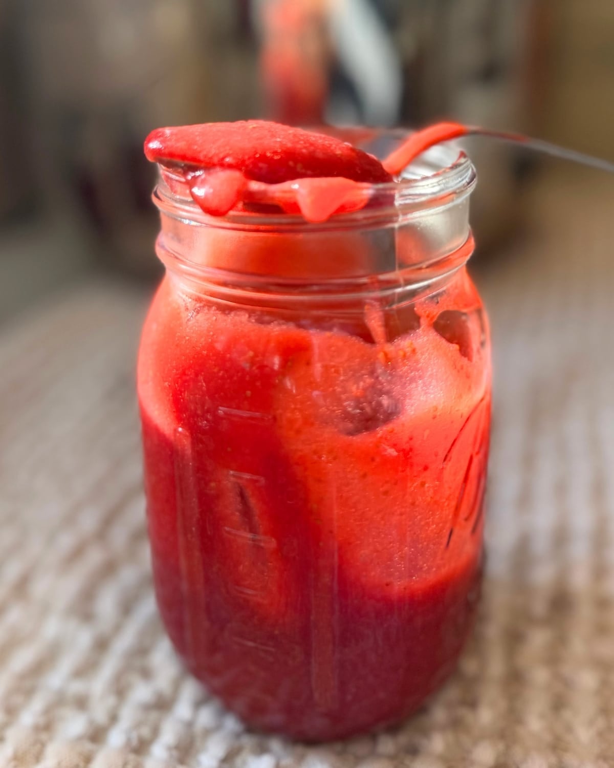low sugar strawberry jam in a pint jar with a spoonful of jam on top
